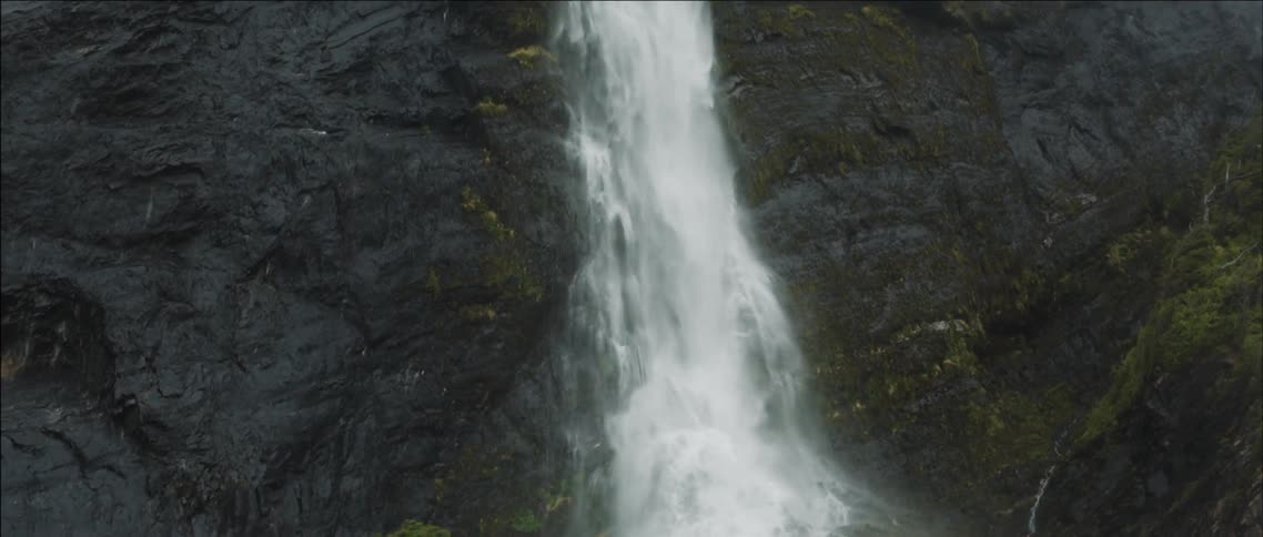 Water cascades down a rocky, moss covered cliff