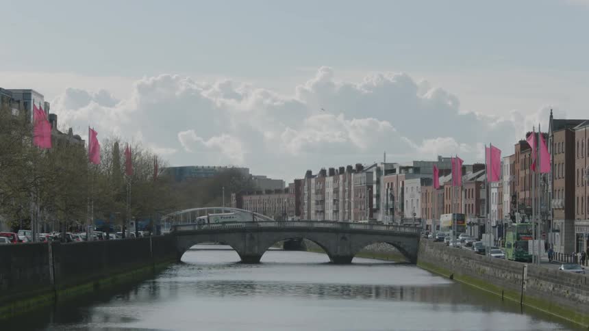View of a river running through a city as traffic passes by on both sides of the river