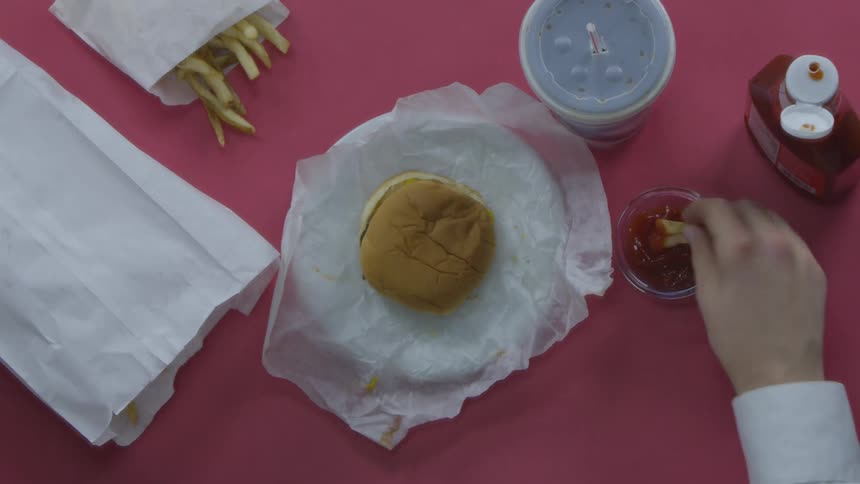Persons arm grabs a french fry and dips it in ketchup