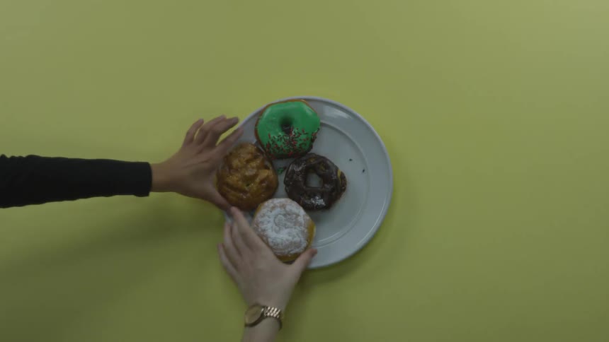 People take doughnut on the plate on the yellow table