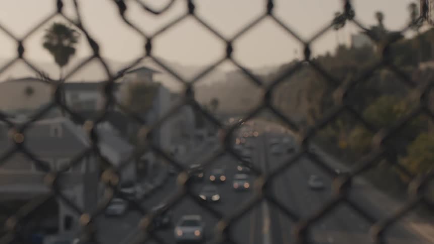 A large road can be seen through a chain link fence on a cloudy day