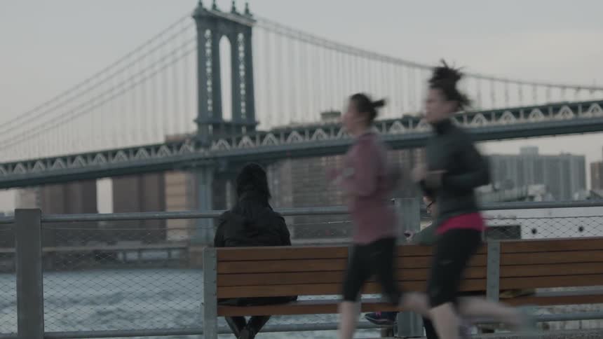 People are running and sitting before a large city on a cloudy day