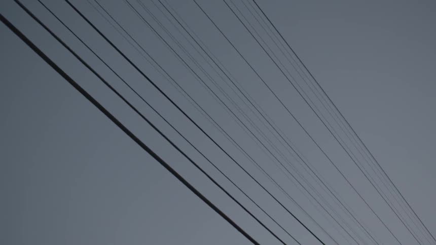 Power lines line a cloudy sky