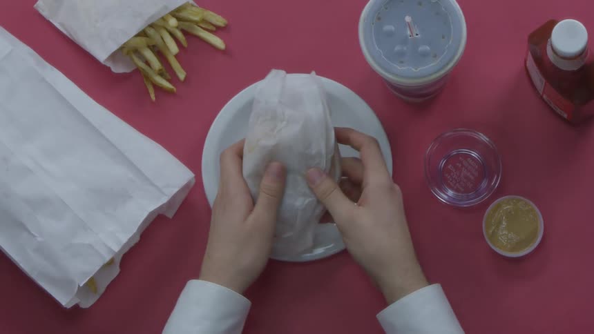 A person is unwrapping a burger