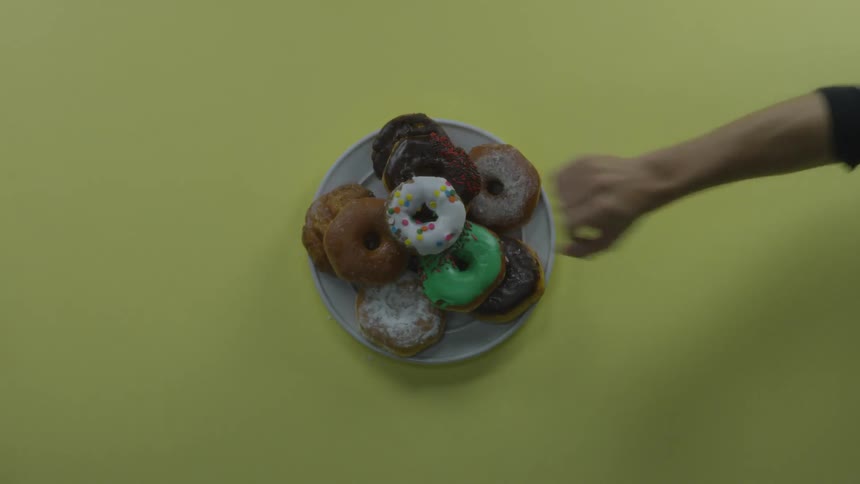 Man tries to get donuts off of plate and an arm extends to stop them