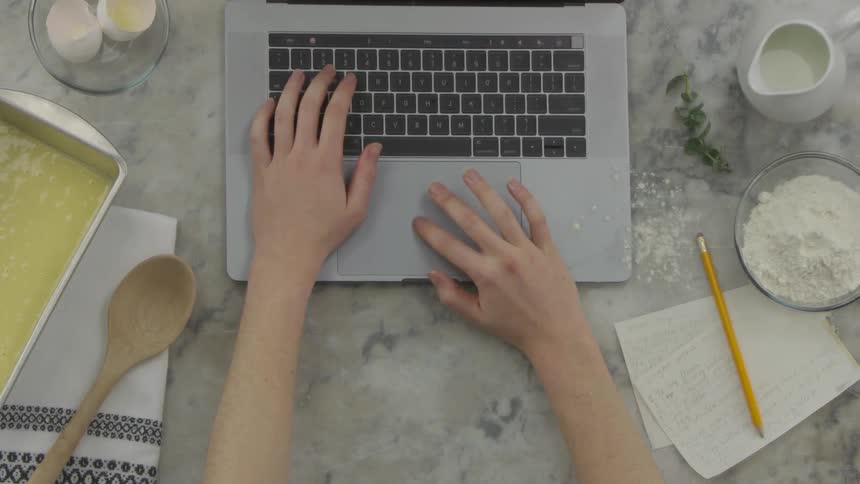 Person types on laptop on kitchen counter