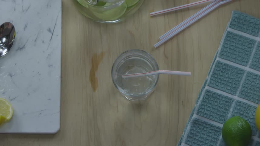 Man placing a plastic straw and a lime slice on a drink