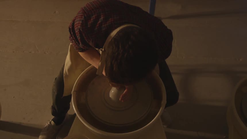 A potter works on sculpting something from clay