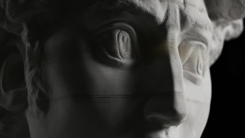 A statue slowly comes apart in a dark room
