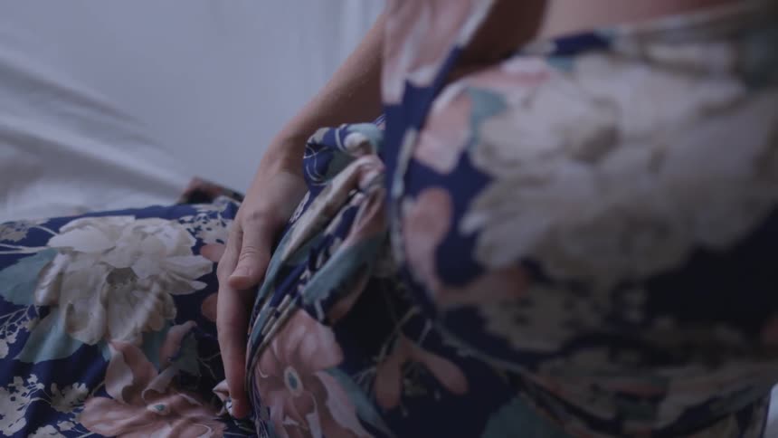 An expecting mother touches her baby bump