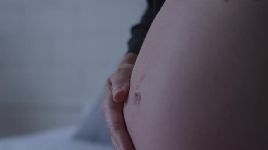 A woman rubbing her pregnant stomach