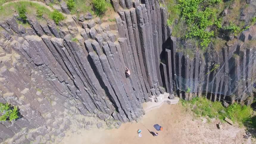 Man climbs the steep rock cliff on a sunny day