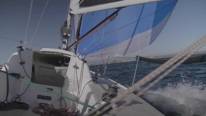 Sailboat sails through ocean kicking up waves