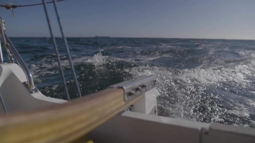 A boat is steered leaving a modest wake under a clear blue sky