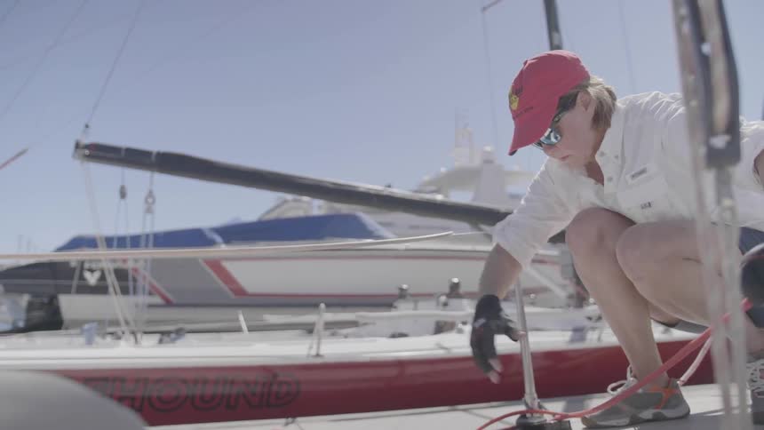 A woman pulls rope through a pulley on a sailboat