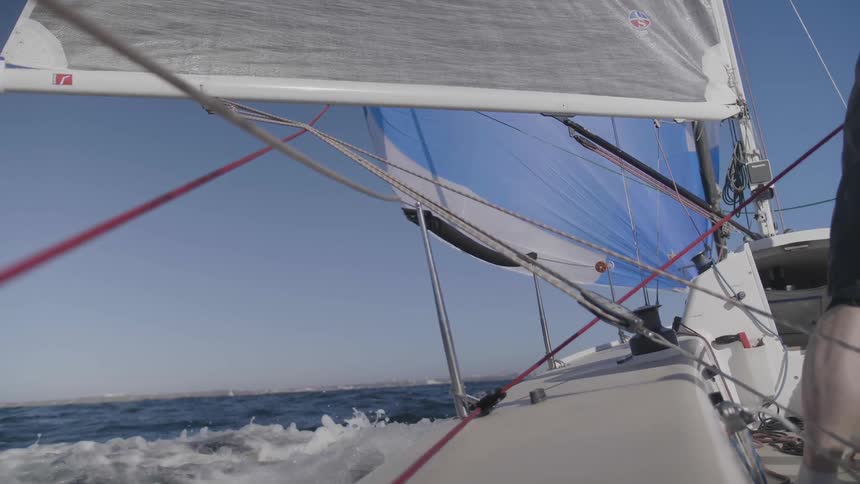 Man pulls lines on sailboat