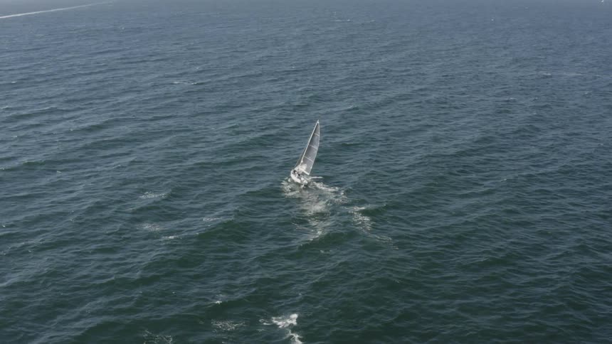A lone sailboat is sailing on the ocean during the day