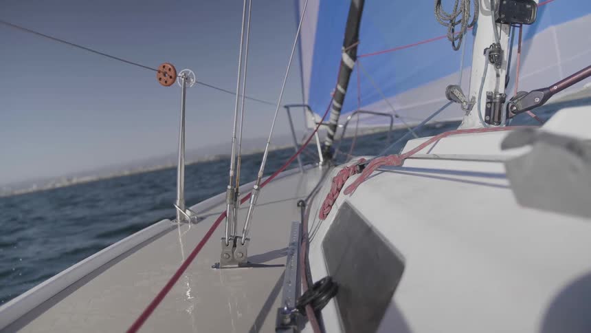 A sailboat with a blue and white sail travels through the water