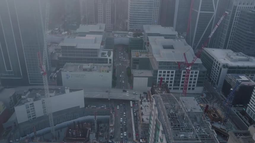 Cars traveling through the city surrounded by buildings at sunrise