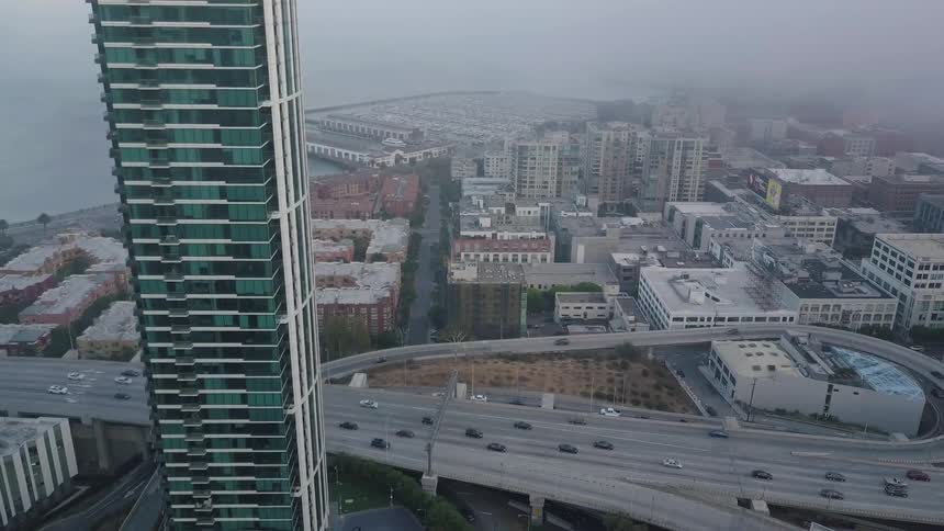 Cars traveling on the highway as the fog rolls in over the city