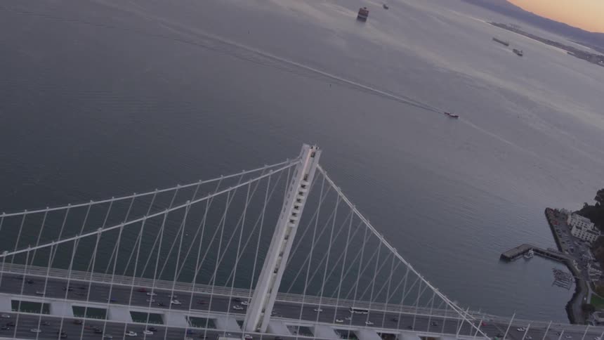 Cars drive over a suspension bridge at sunset