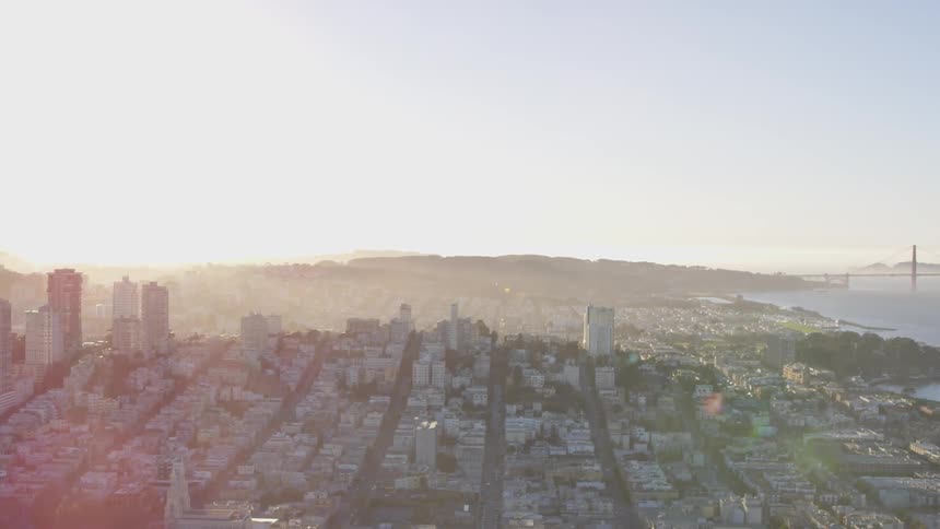 A panoramic view of a city skyline with a suspension bridge in the background