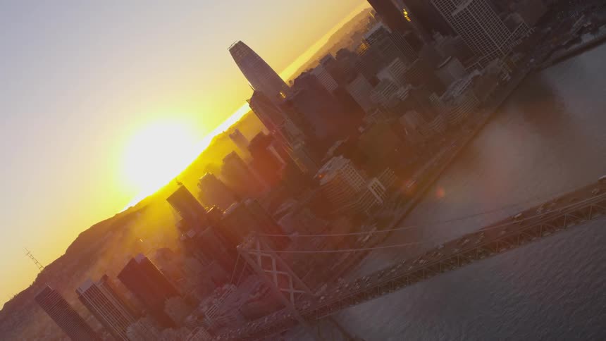 A bridge over a body of water leading to city at sunset