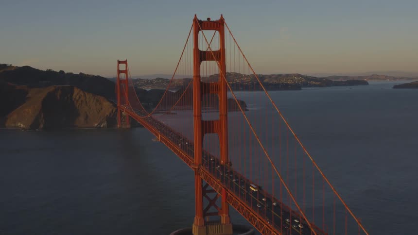 Cars and trucks travel across the golden gate bridge at sunset