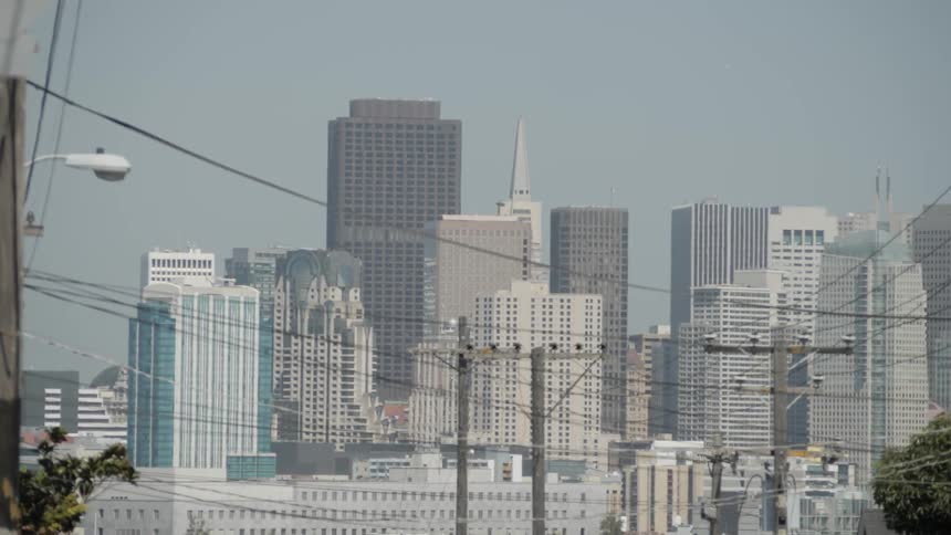 City buildings stand tall behind telephone and electrical wires on poles