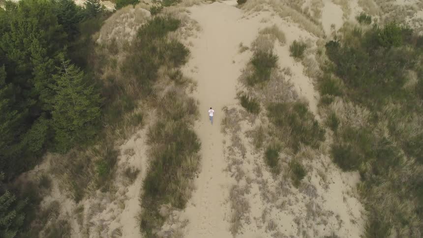 Lone runner climbing a sandy hill