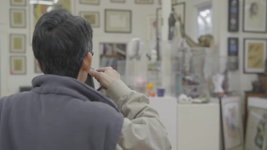 A person picks up a cup off a table and drinks while admiring art