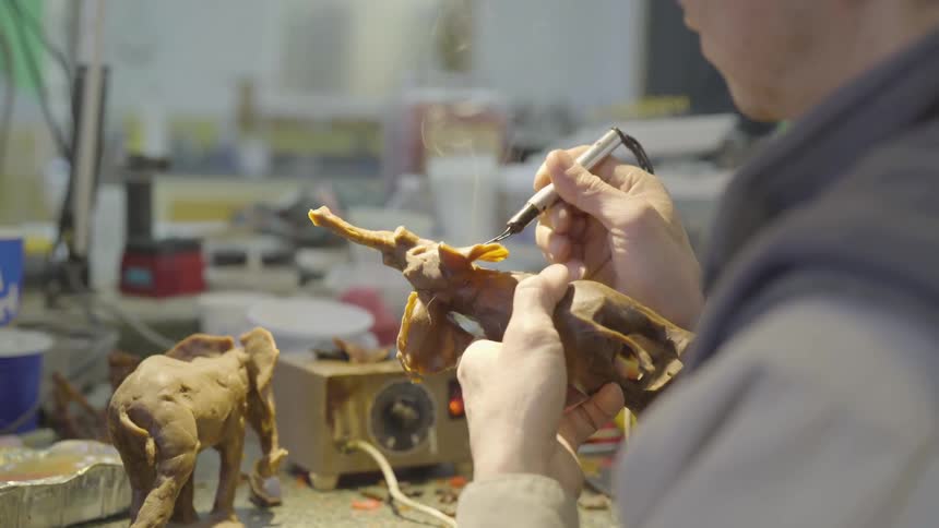 Man uses tool to mold elephant sculpture