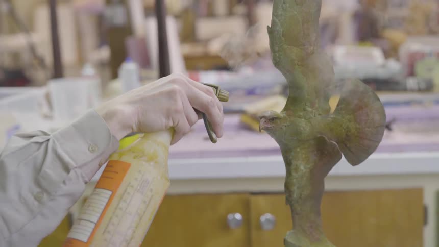 A person uses a torch to glaze a sculpture