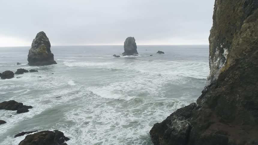 Waves ebb flow and crash against a rocky coastline and outcrops