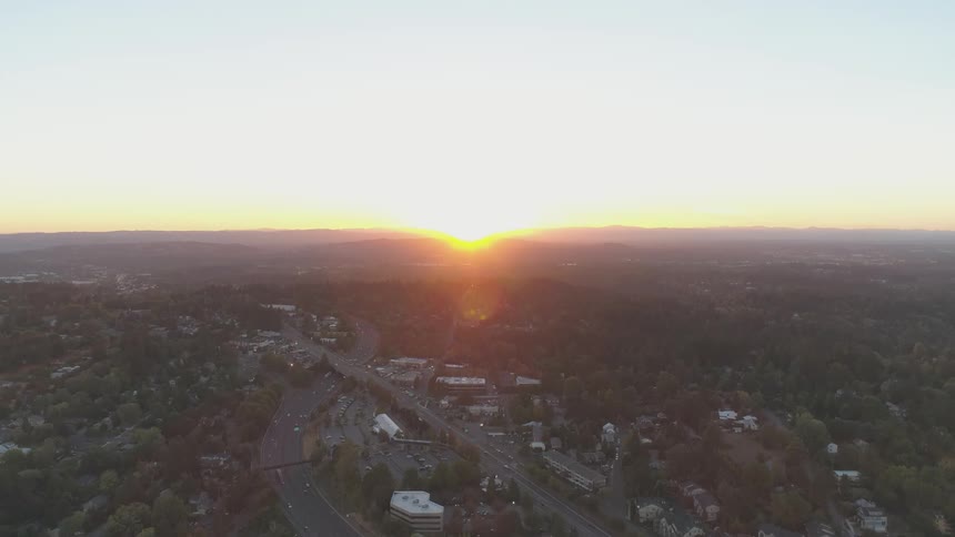 The sun sets over cars driving on a city road