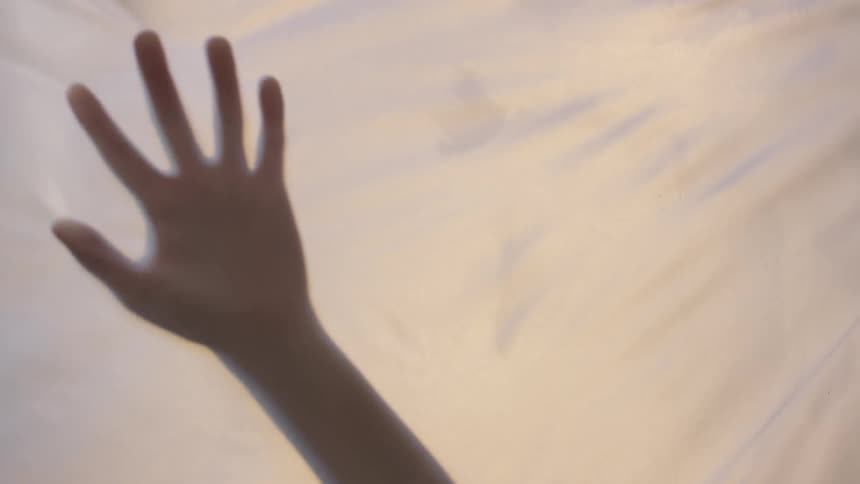 A person sliding their hands along a sheet of cloth