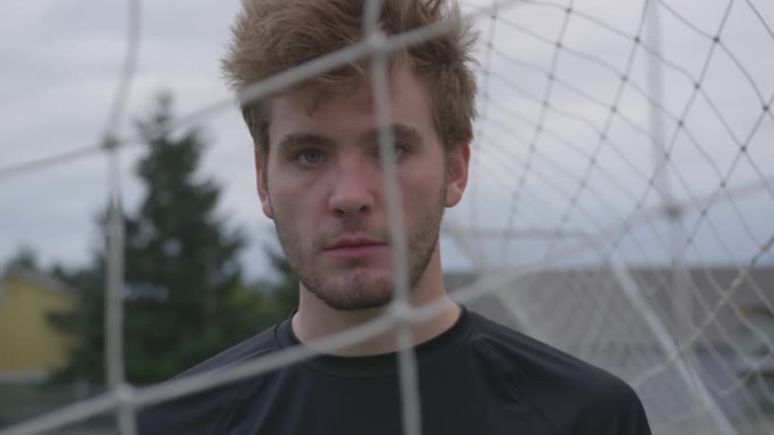 Soccer player looks into the camera through a net