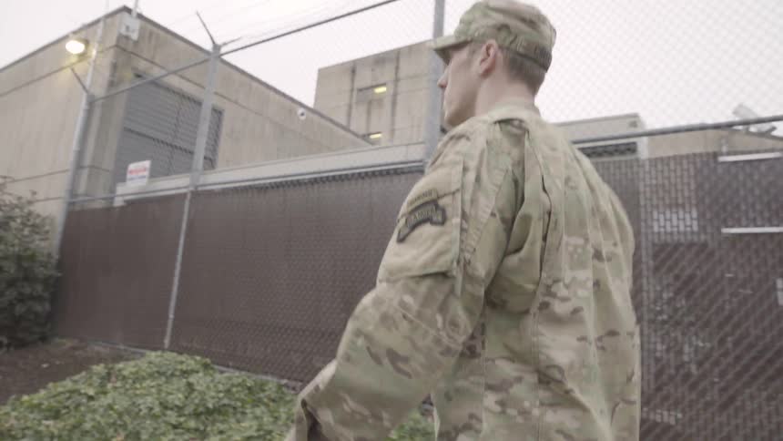 Soldier walks next to a building