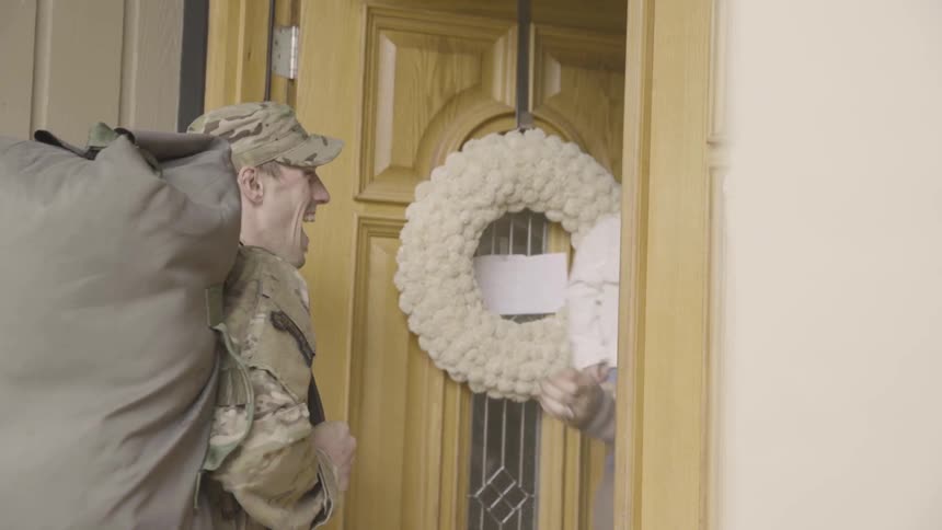 Woman and child greet returning military man at door
