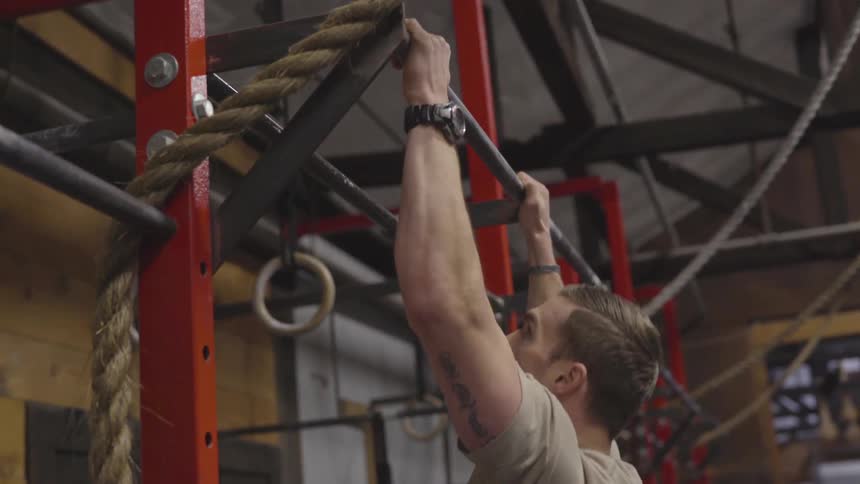 Strong active caucasian male impressively does pull ups at the gym while wearing a nice watch
