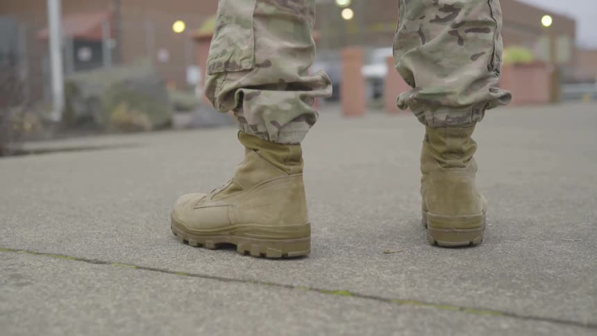 A person wearing boots and camo pants standing in the road
