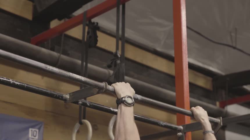 A man wearing camo doing pull ups in a gym