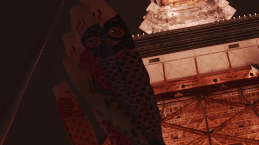 Fish shaped flags blowing beneath a brightly lit structure