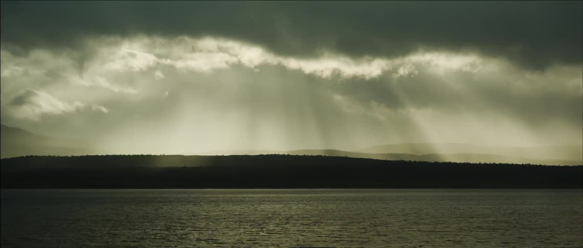 Sun is beginning to shine through some clouds on the water