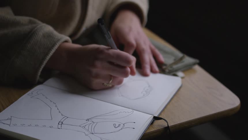 A person is drawing in a notebook