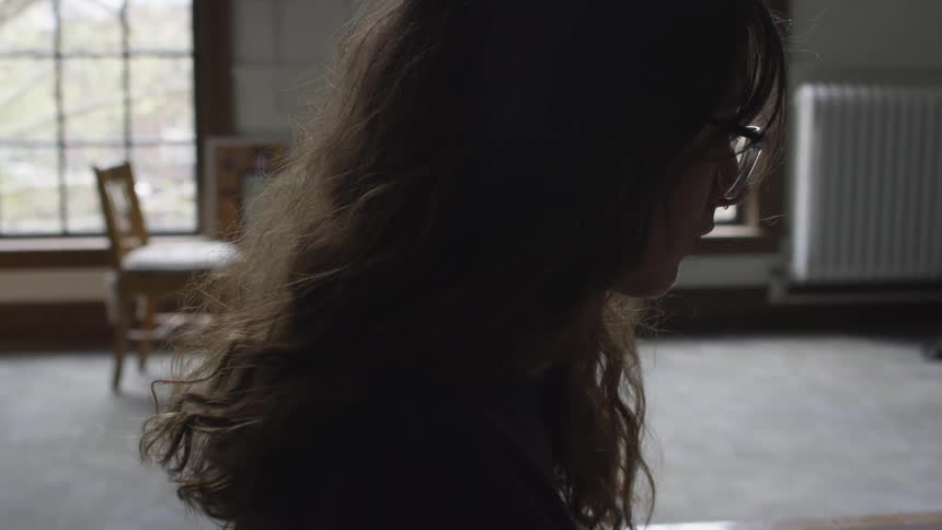 A woman is in a classroom sitting down