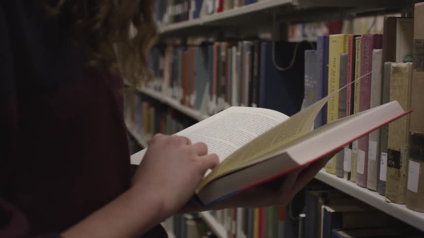 A woman is reading a book in a library
