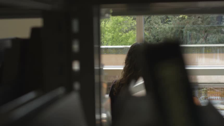 Woman sitting at a table looking through a window