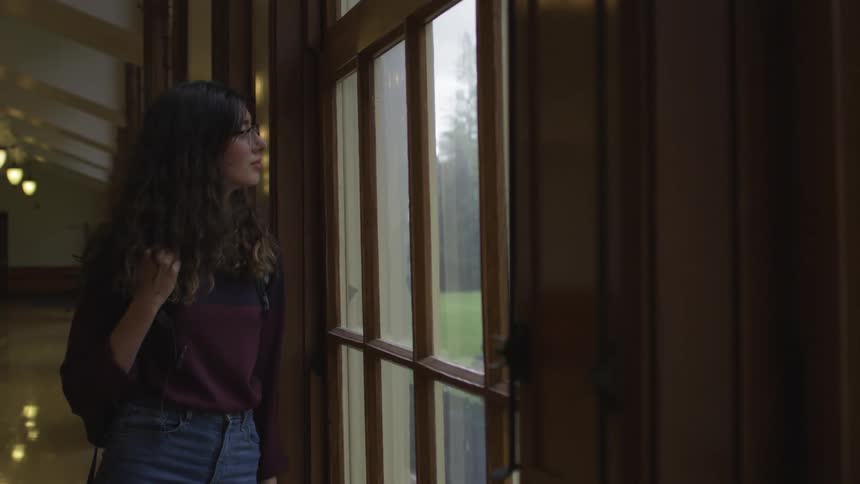 Woman looks out a window onto a lawn