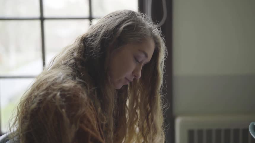 A female student with long hair reads and turns the page of her workbook